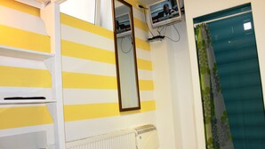 Una habitación con pared a rayas amarillas y blancas, un radiador blanco, un espejo y una cortina de ducha verde.