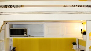 Una kitchenette compacta con microondas, un refrigerador pequeño y dos sillas.