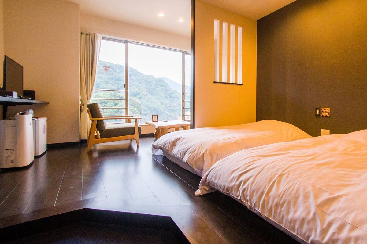 A hotel room with a bed, a chair, a desk, and a view of the outdoors.