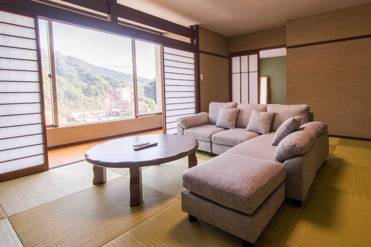 A traditional Japanese-style room with tatami flooring, a low sofa, and a small table.