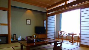 A traditional Japanese room with tatami flooring, a low table, a television, and a sliding door leading to a balcony. - Kirishima Onsen Oyado Hana Mizuki (Kirishima)