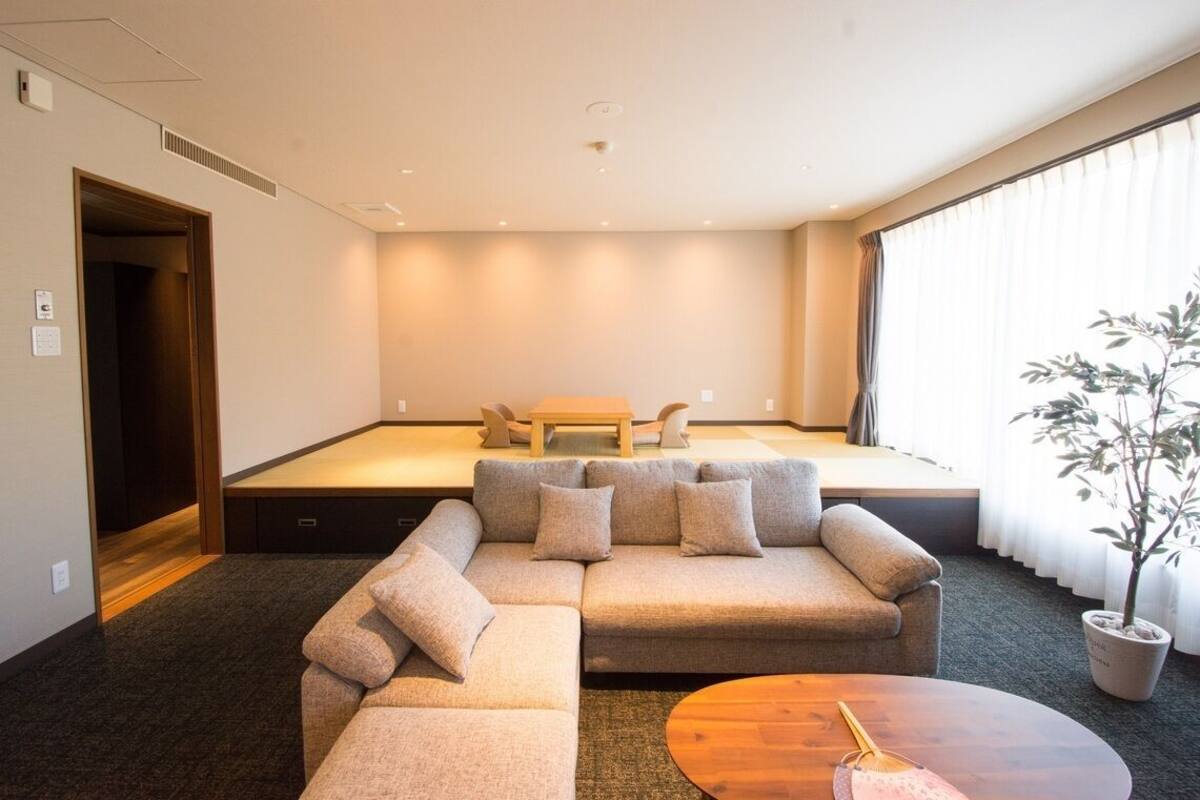 A modern living room with a sectional sofa, a coffee table, and a small stage area.