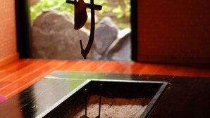 A close-up of a rustic wooden table with a metal object hanging from a string. - Kirishima Onsen Oyado Hana Mizuki (Kirishima)