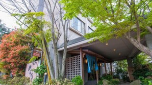 A traditional Japanese building with a covered entrance, a stone pathway, and lush greenery. - Kirishima Onsen Oyado Hana Mizuki (Kirishima)