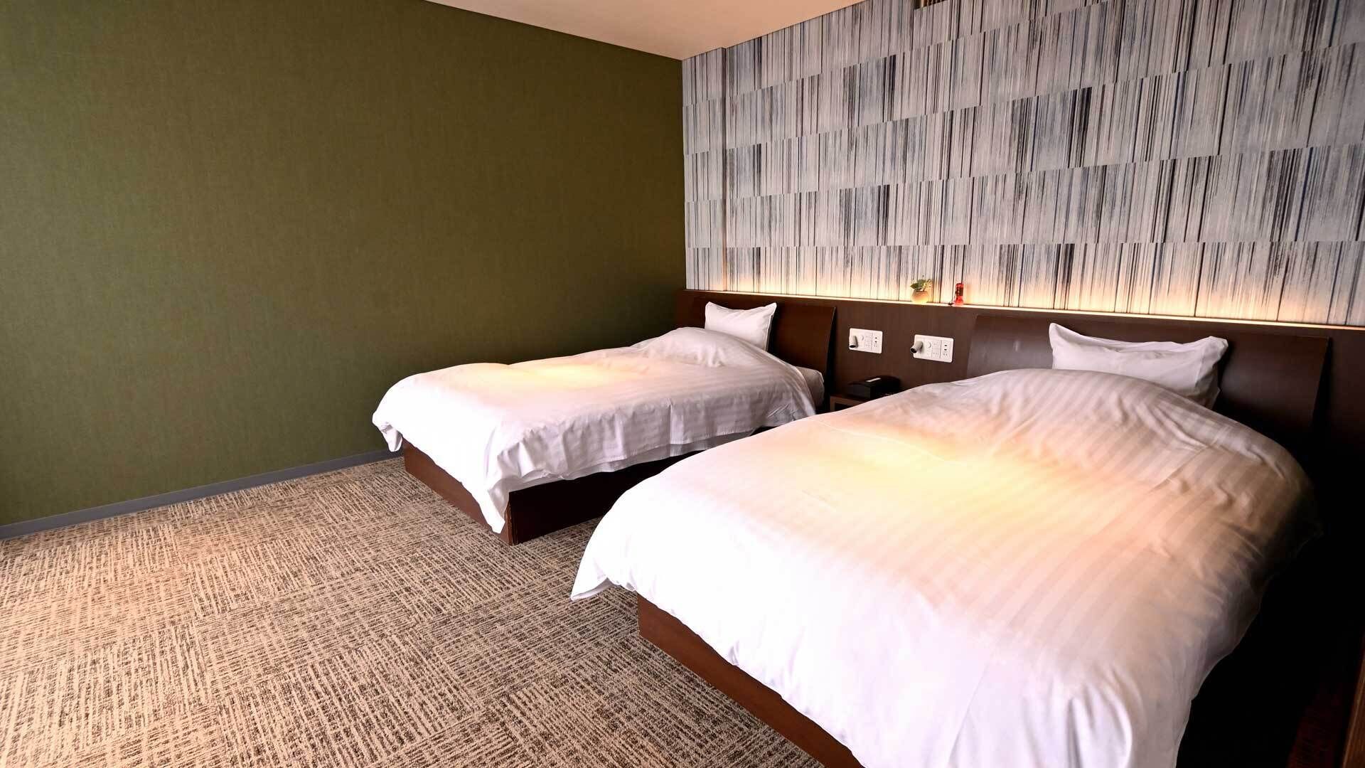 Habitación de hotel con dos camas, un papel tapiz estampado y suelo alfombrado.