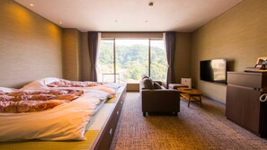 Habitación de hotel con una cama grande, un sofá, un televisor y vistas al exterior.