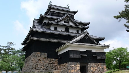 A traditional Japanese castle with multiple tiers and a stone base.