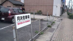 A parking sign in front of a building with a chain-link fence. - Ryokan Asahikan (Yasugi)