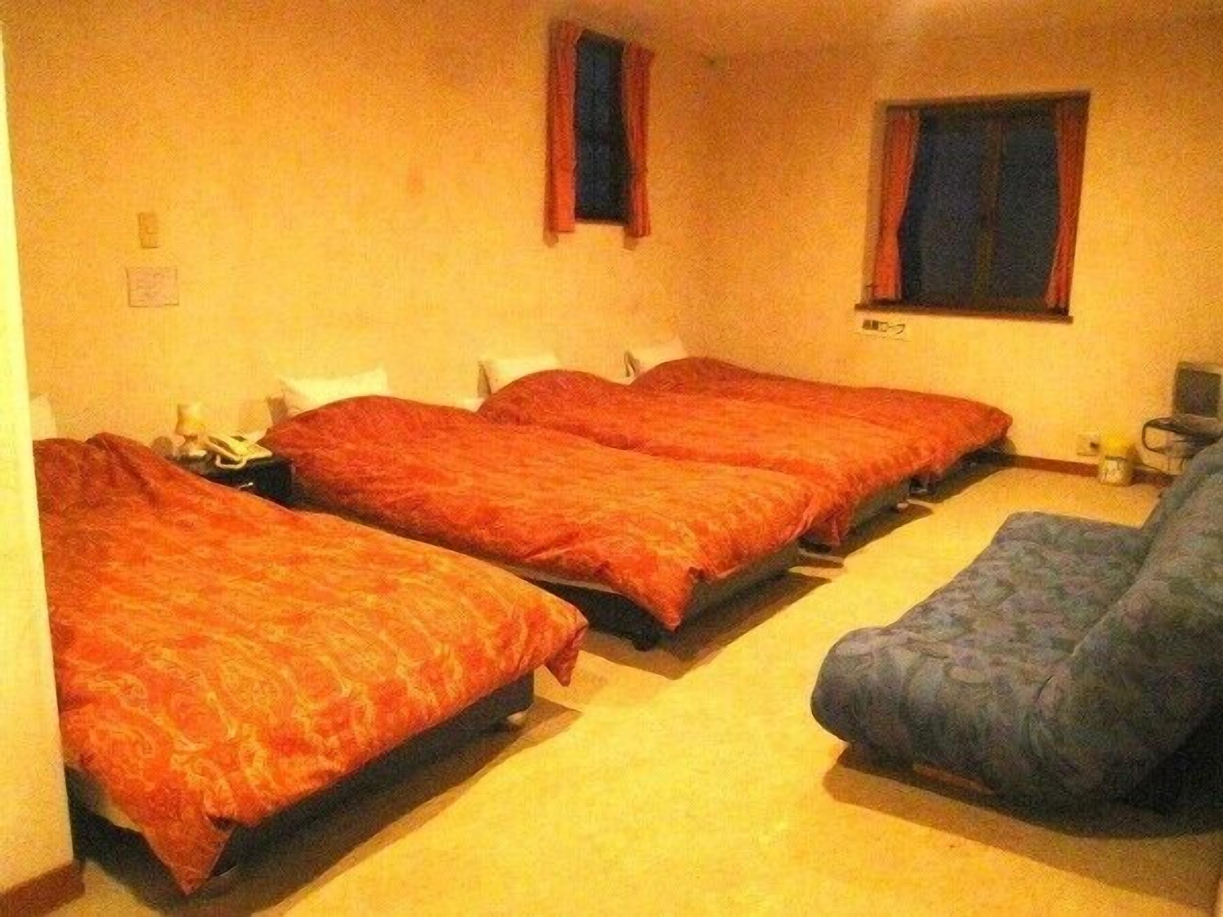 A room with two beds, a chair, and a small table.
