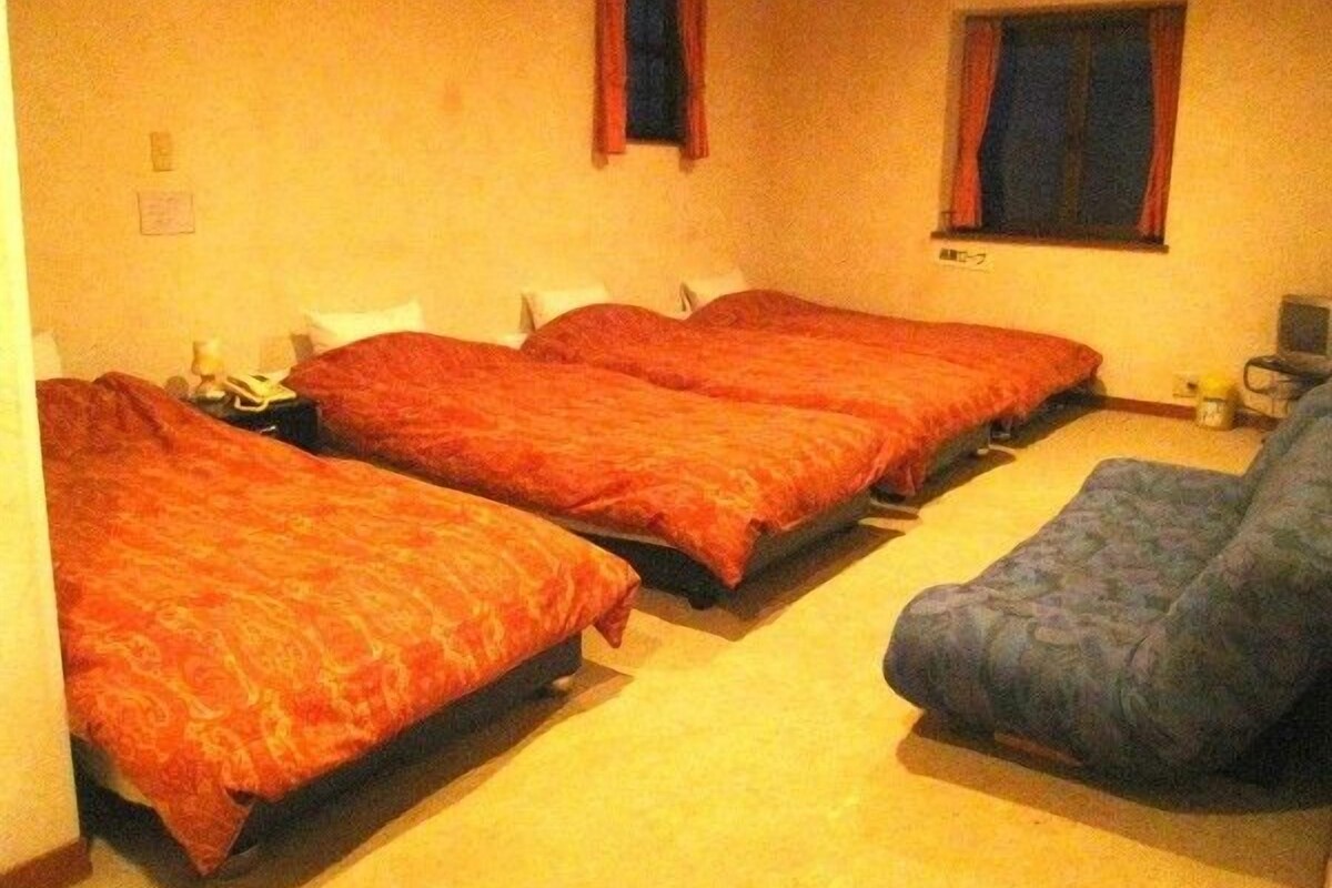 A room with two beds, a chair, and a small table.