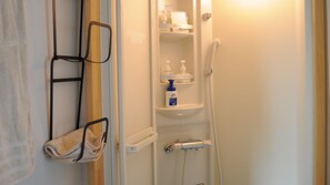 Ein Badezimmer mit Handtuchhalter, Ablagefläche für Toilettenartikel und Duschbereich.