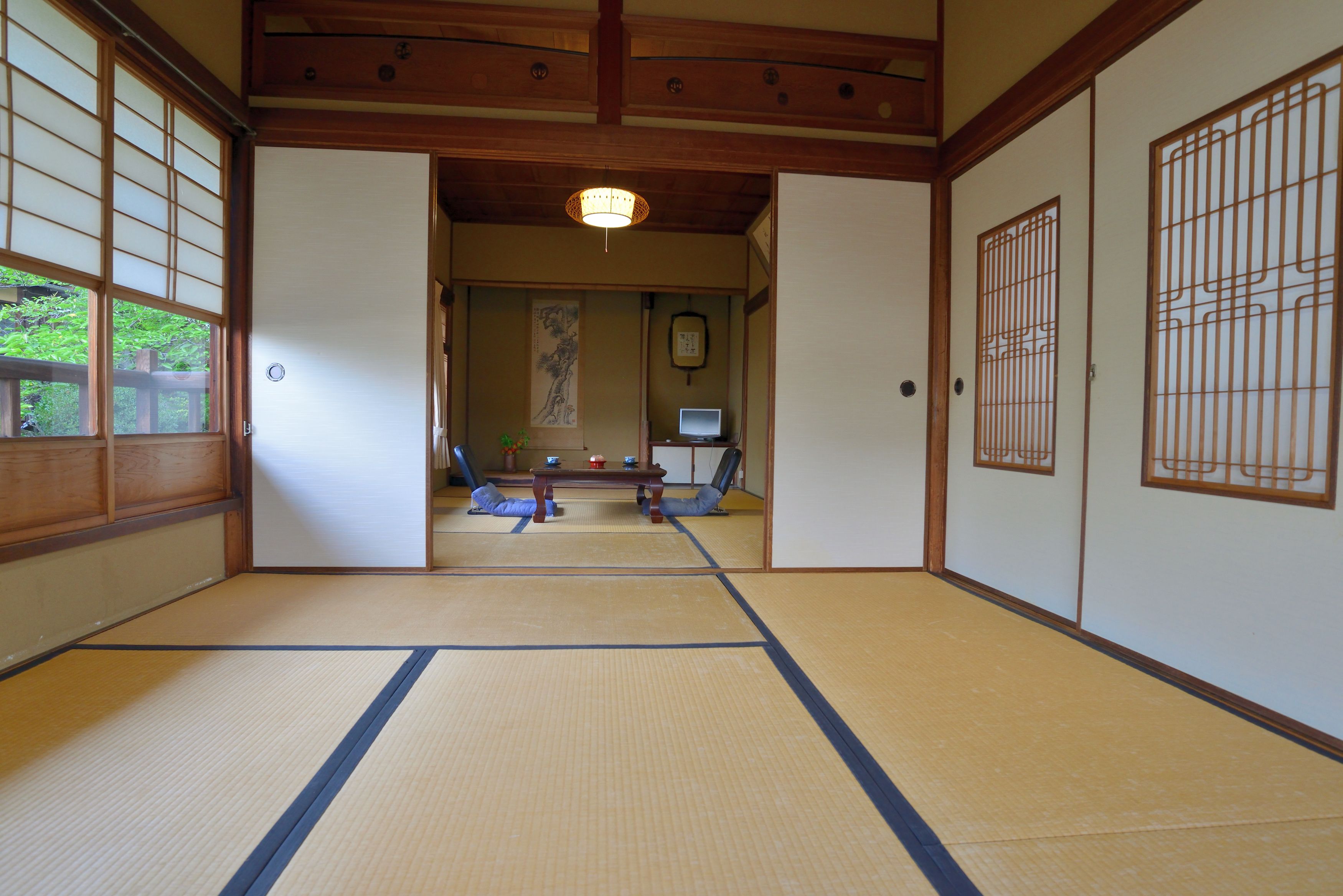 A traditional Japanese room with tatami flooring, sliding doors, and a low ceiling.