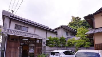 Traditional Japanese architecture with a tiled roof and wooden facade, set amidst lush greenery.