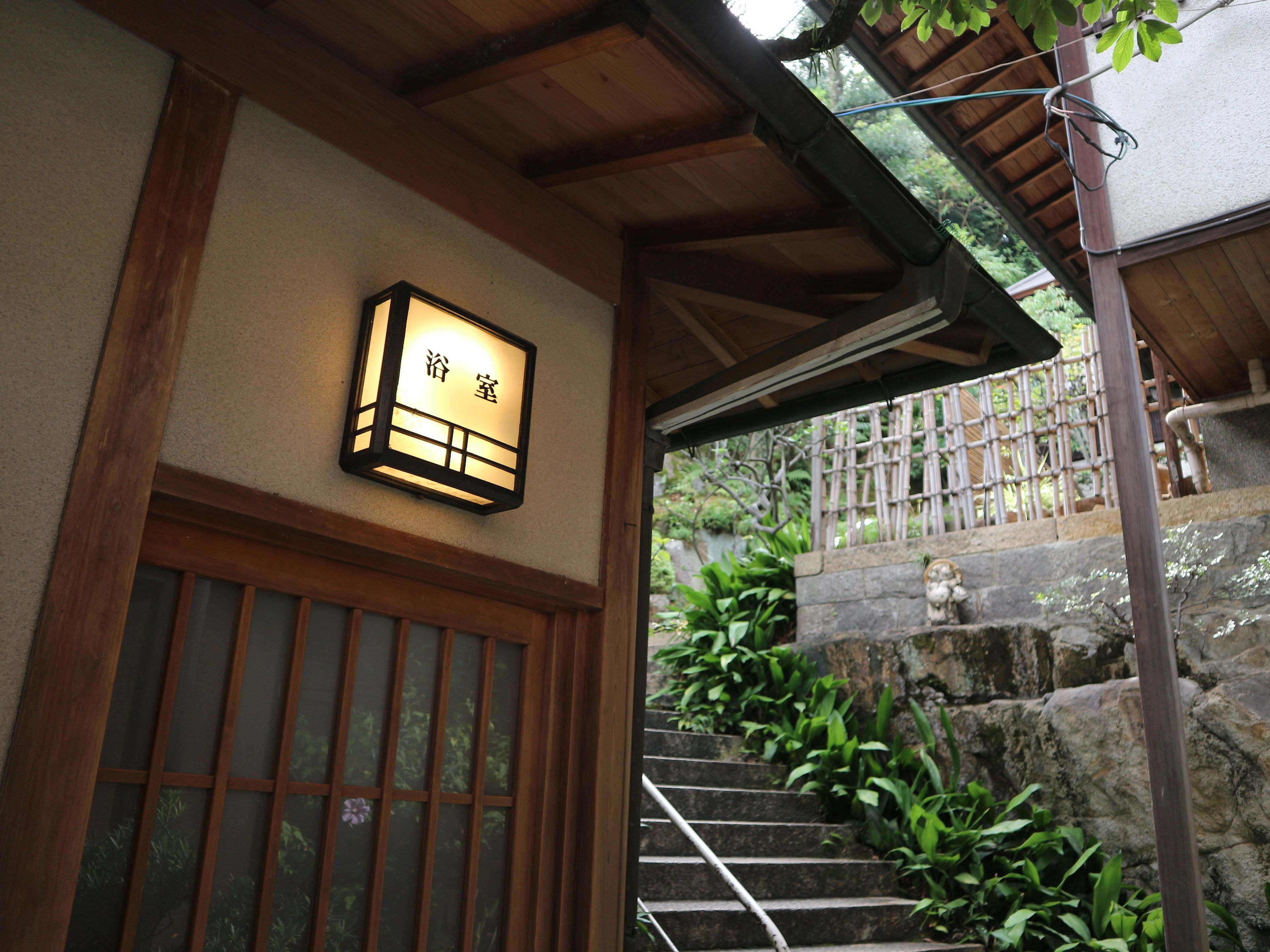 Un edificio tradicional japonés con una entrada de madera y una escalera de piedra que conduce hacia él.