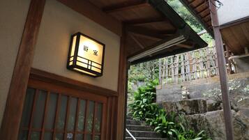Un edificio tradicional japonés con una entrada de madera y una escalera de piedra que conduce hacia él.