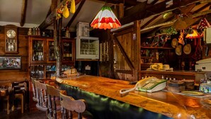 A bar with wooden furniture, a telephone, and various bottles and glasses. - Hope Lodge (Chino)