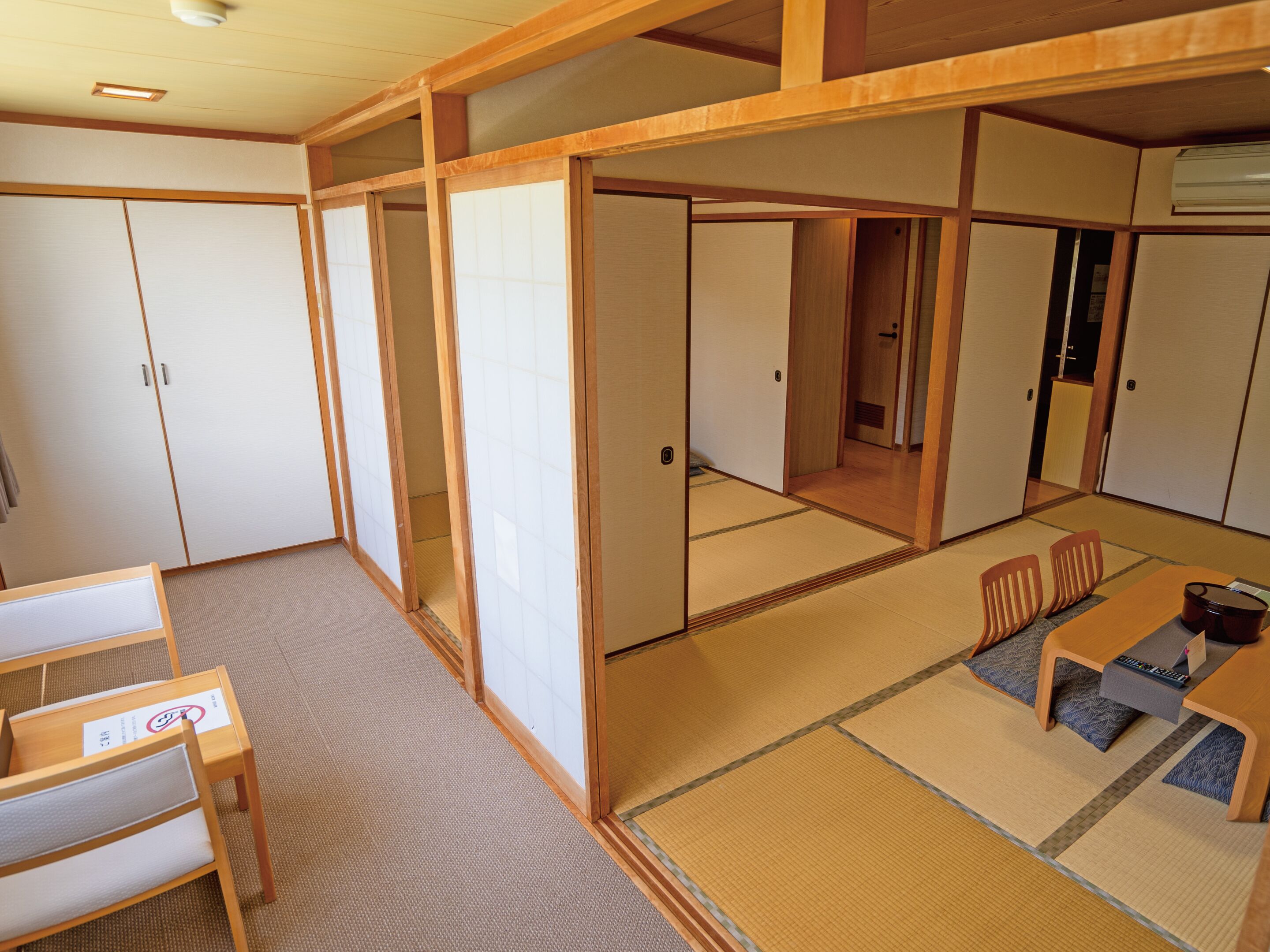 A traditional Japanese room with tatami flooring, sliding doors, and a low table with chairs.