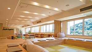 Un interior moderno con una amplia zona de comedor, diversas opciones de asientos y grandes ventanales con vistas a zonas verdes.