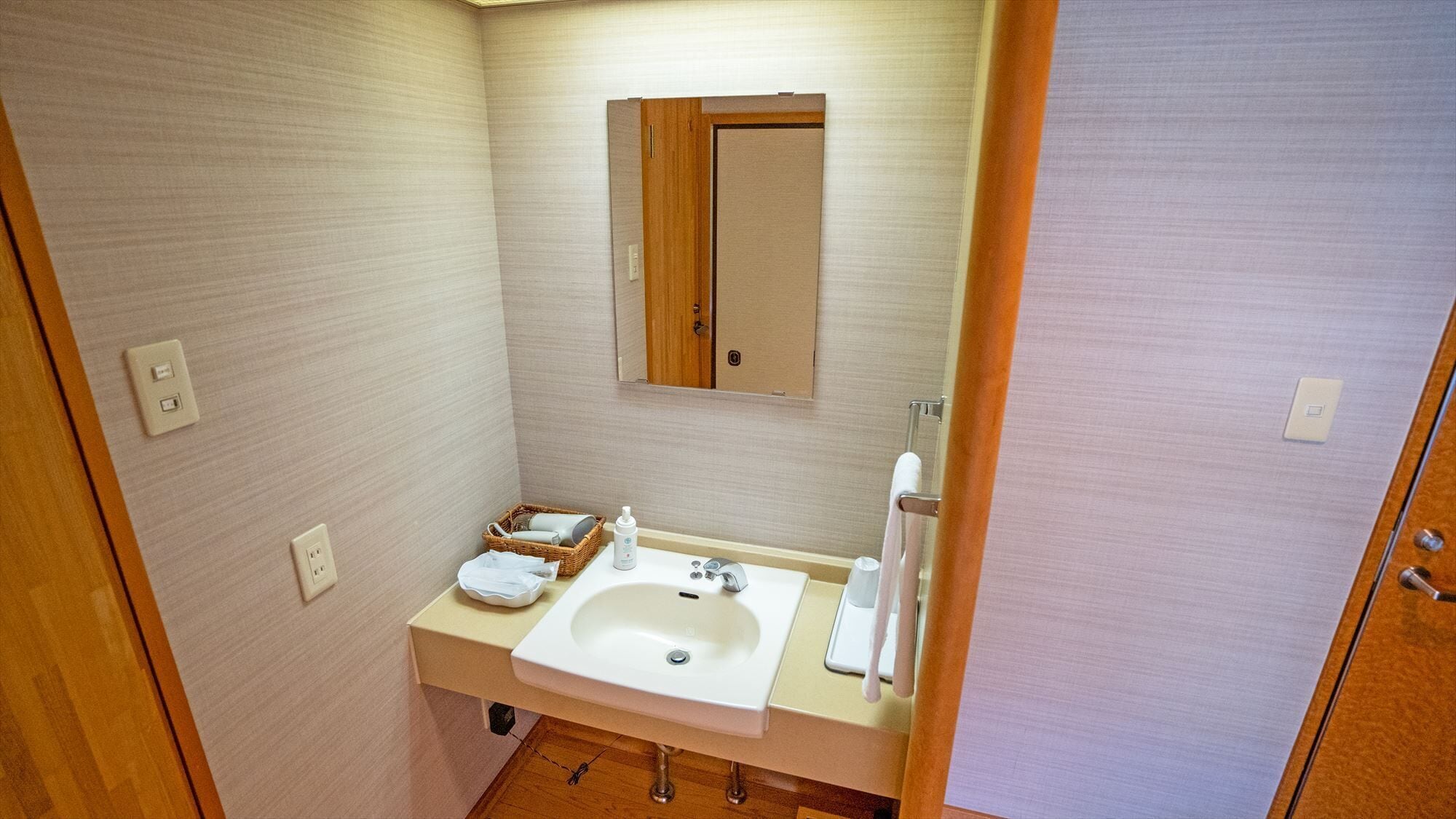 Un banyet petit amb un lavabo, mirall i una porta de fusta.
