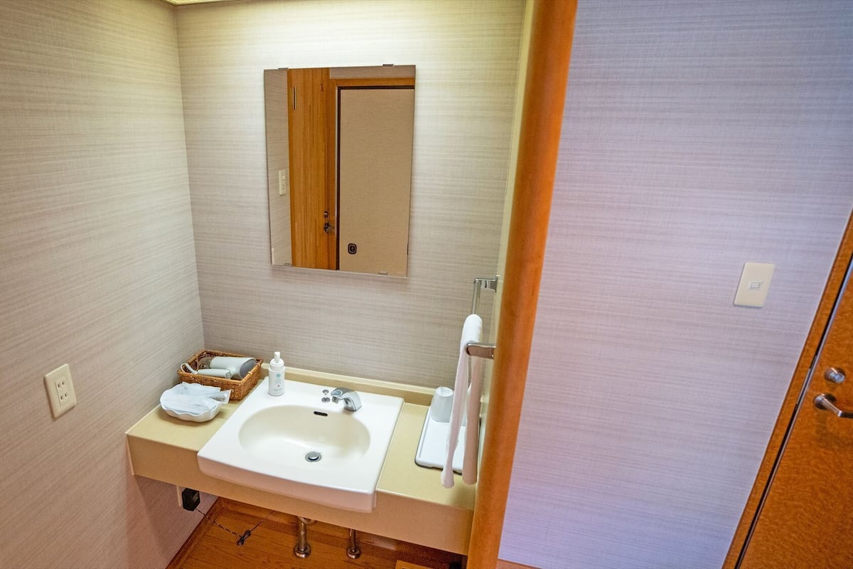 A small bathroom with a sink, mirror, and a wooden door.