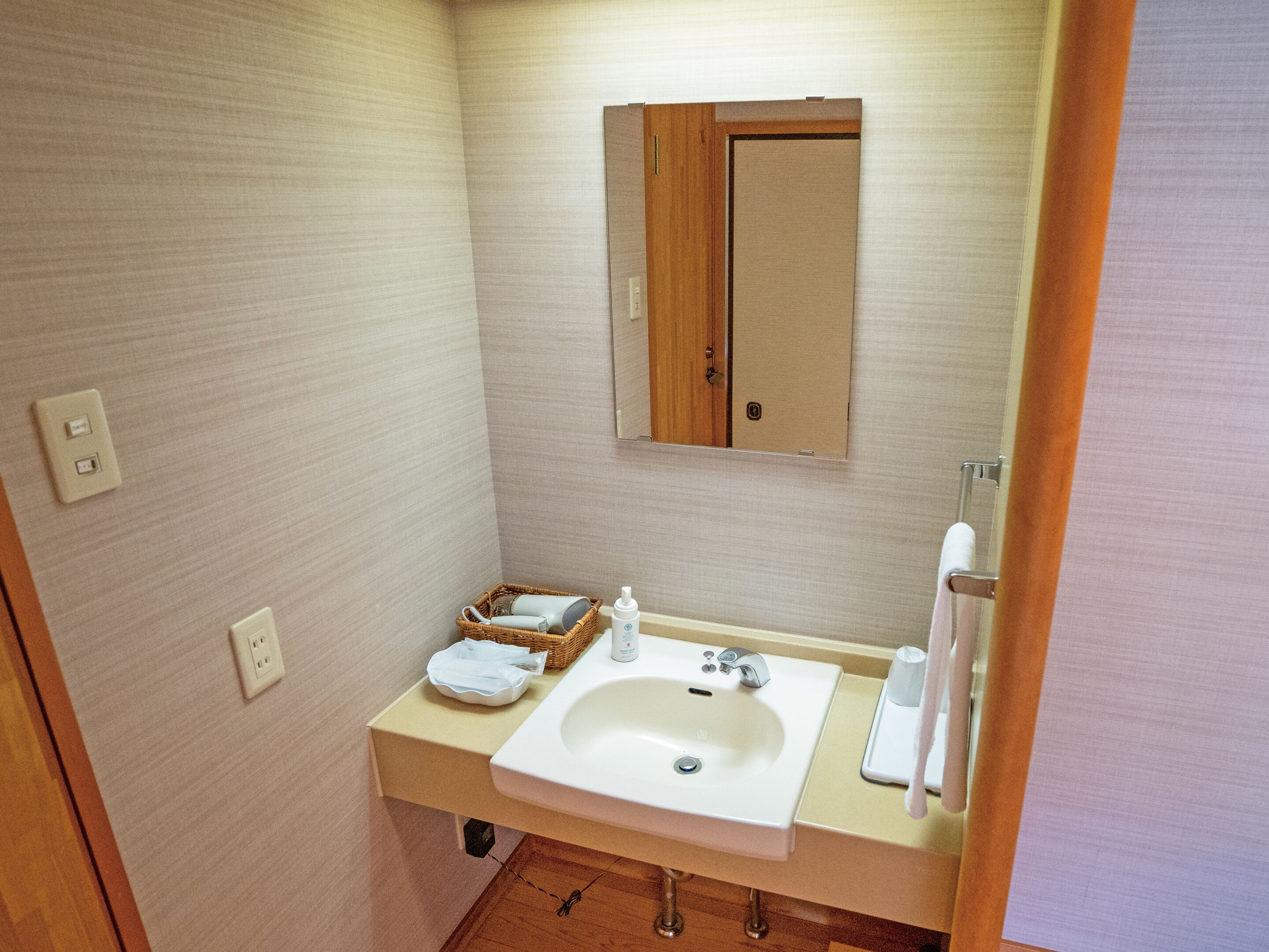 A small bathroom with a sink, mirror, and a towel rack.