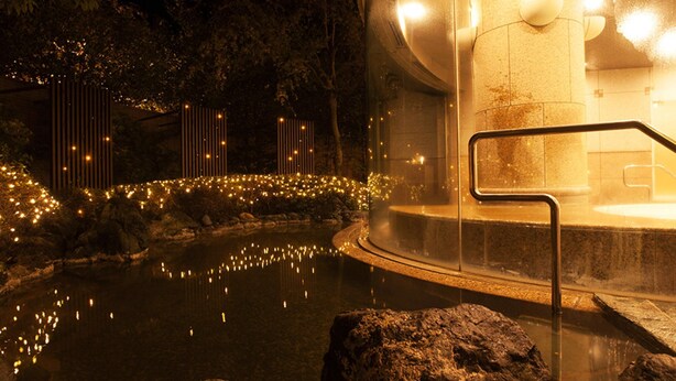 A hot spring area with a circular pool, stone steps, and a glass enclosure with a hot tub. - Sunhills Hotel (Utsunomiya)