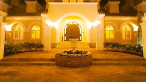 A grand entrance with a central archway, a large planter with flowers, and a symmetrical facade with multiple windows. - Sunhills Hotel (Utsunomiya)