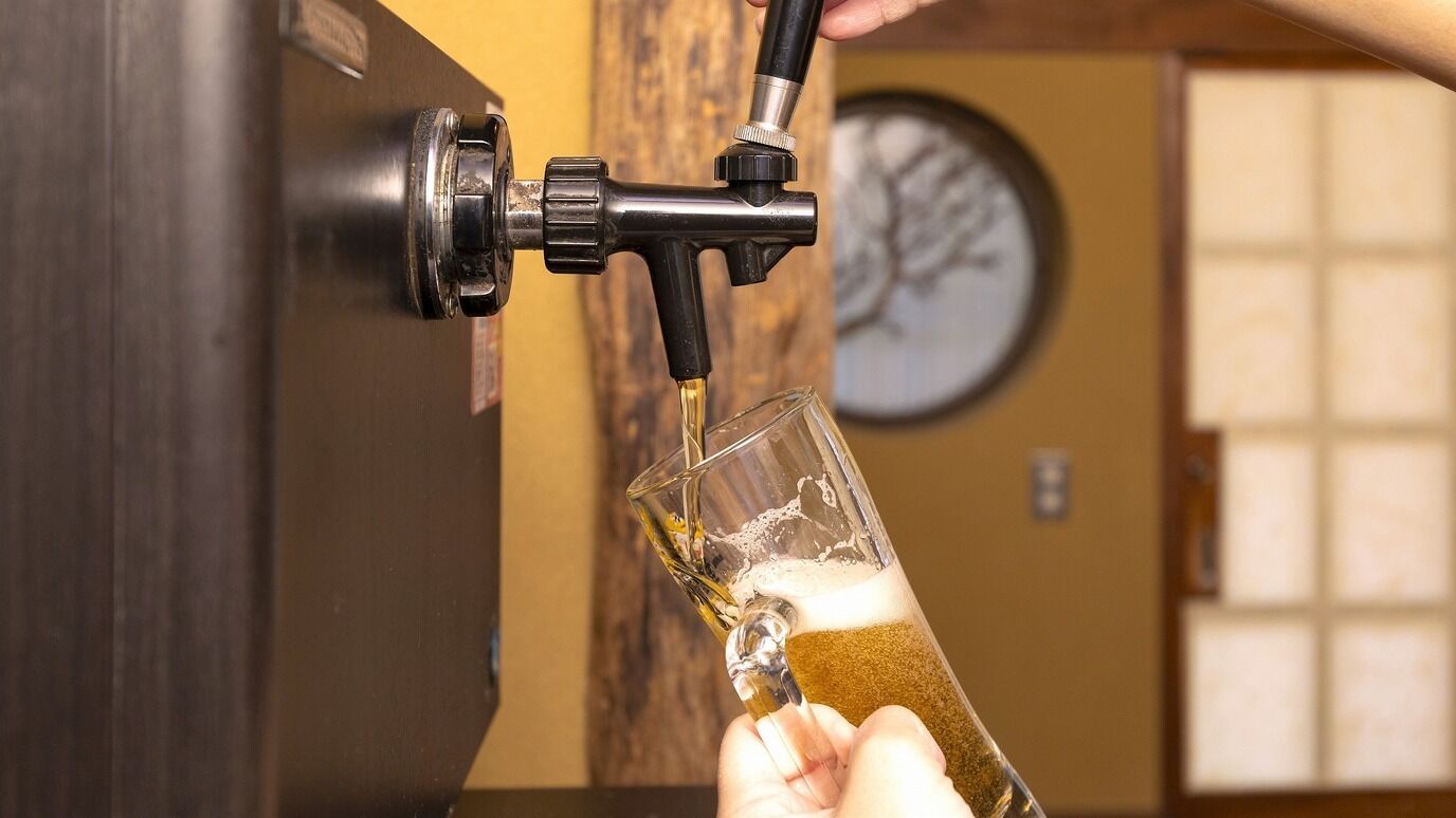 A hand holding a glass under a tap, water flowing into it.
