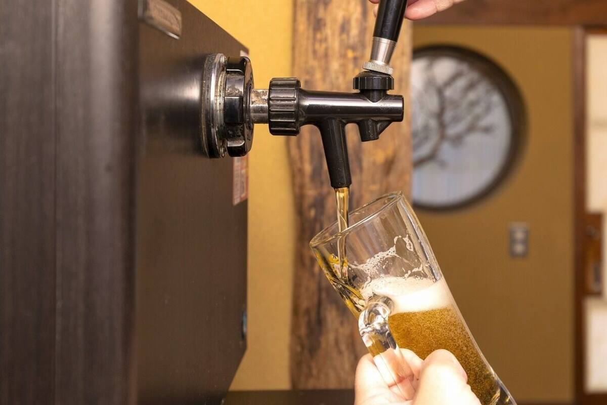 A hand holding a glass under a tap, water flowing into it.