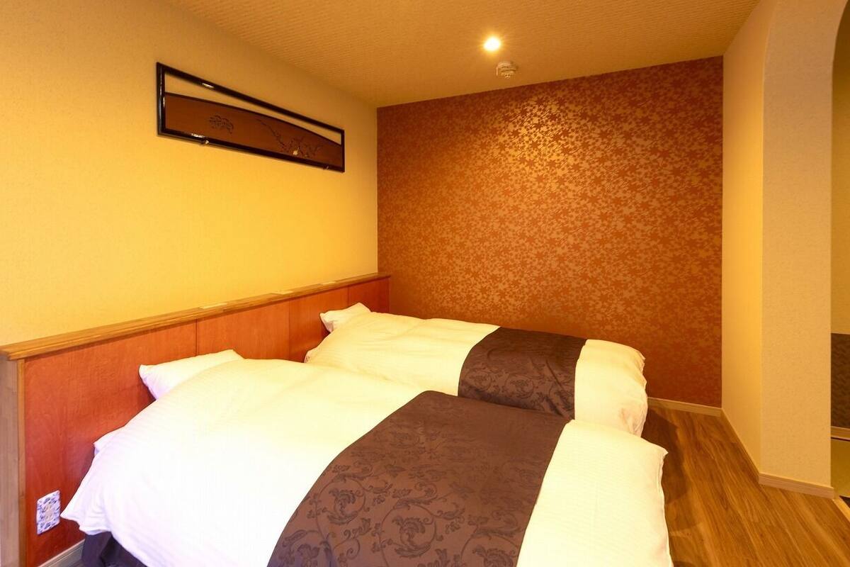 A hotel room with a bed, a wooden headboard, a patterned wall, and a ceiling light.