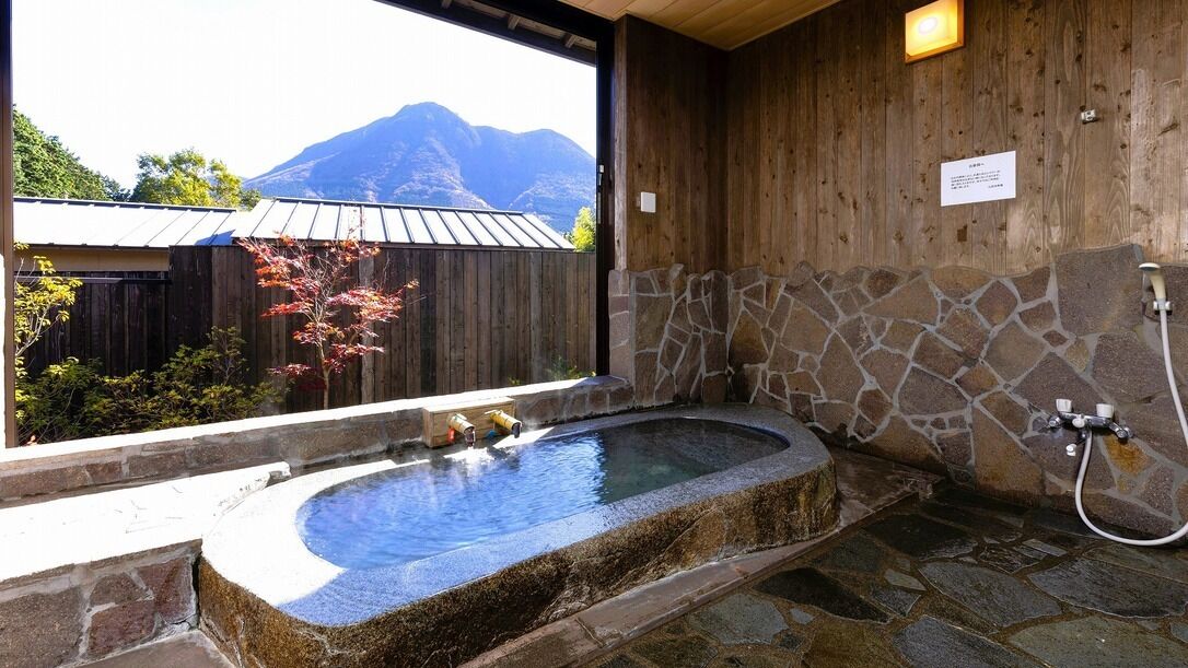 A stone hot tub with a wooden wall and a stone shower area.