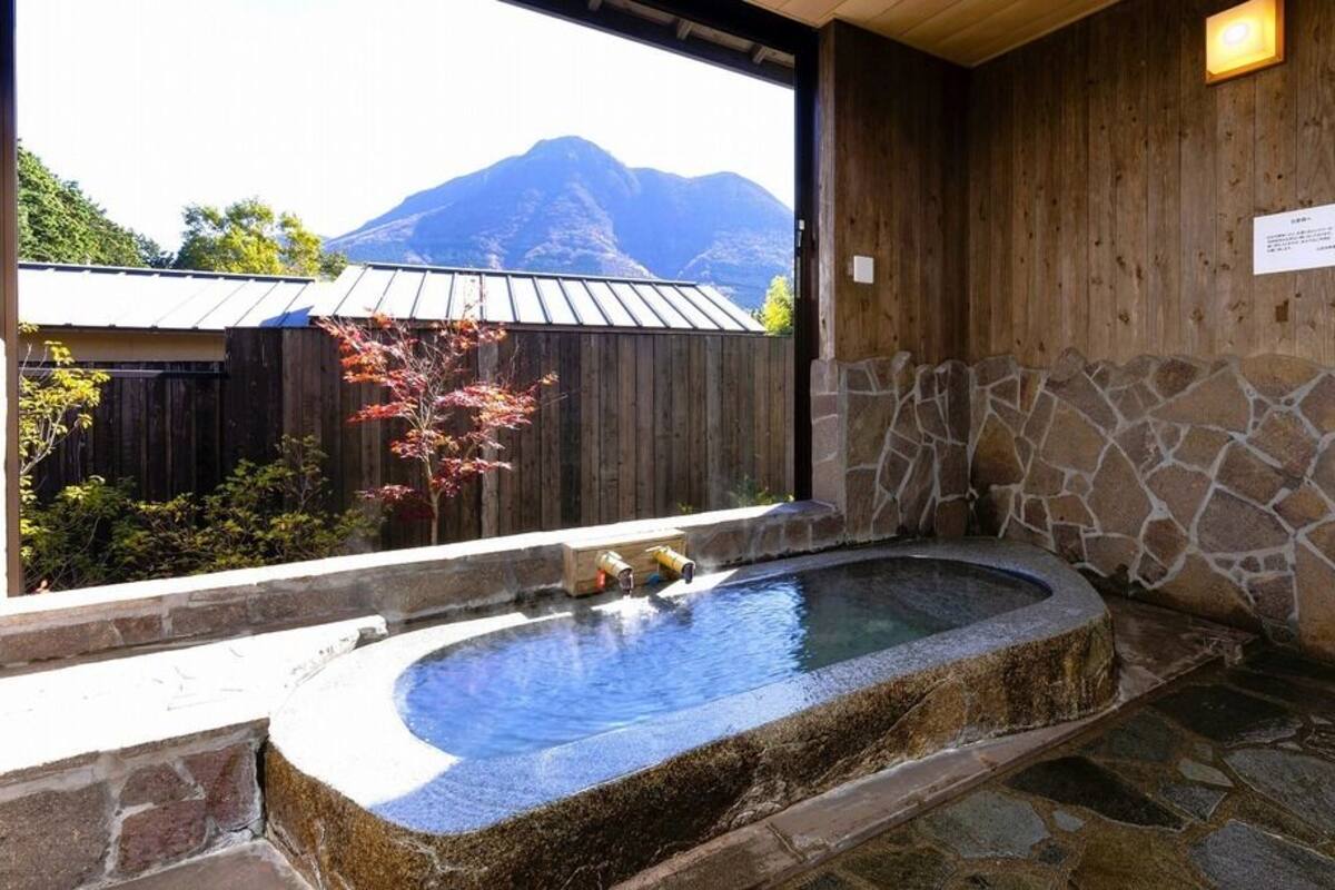 A stone hot tub with a wooden wall and a stone shower area.