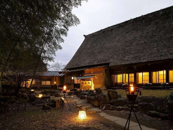 Un bâtiment japonais traditionnel, doté d’un toit de chaume, de lanternes en pierre et d’une porte d’entrée en bois.