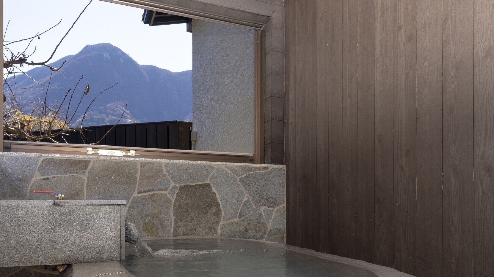 A stone-tiled hot tub area with a view of mountains through a window.
