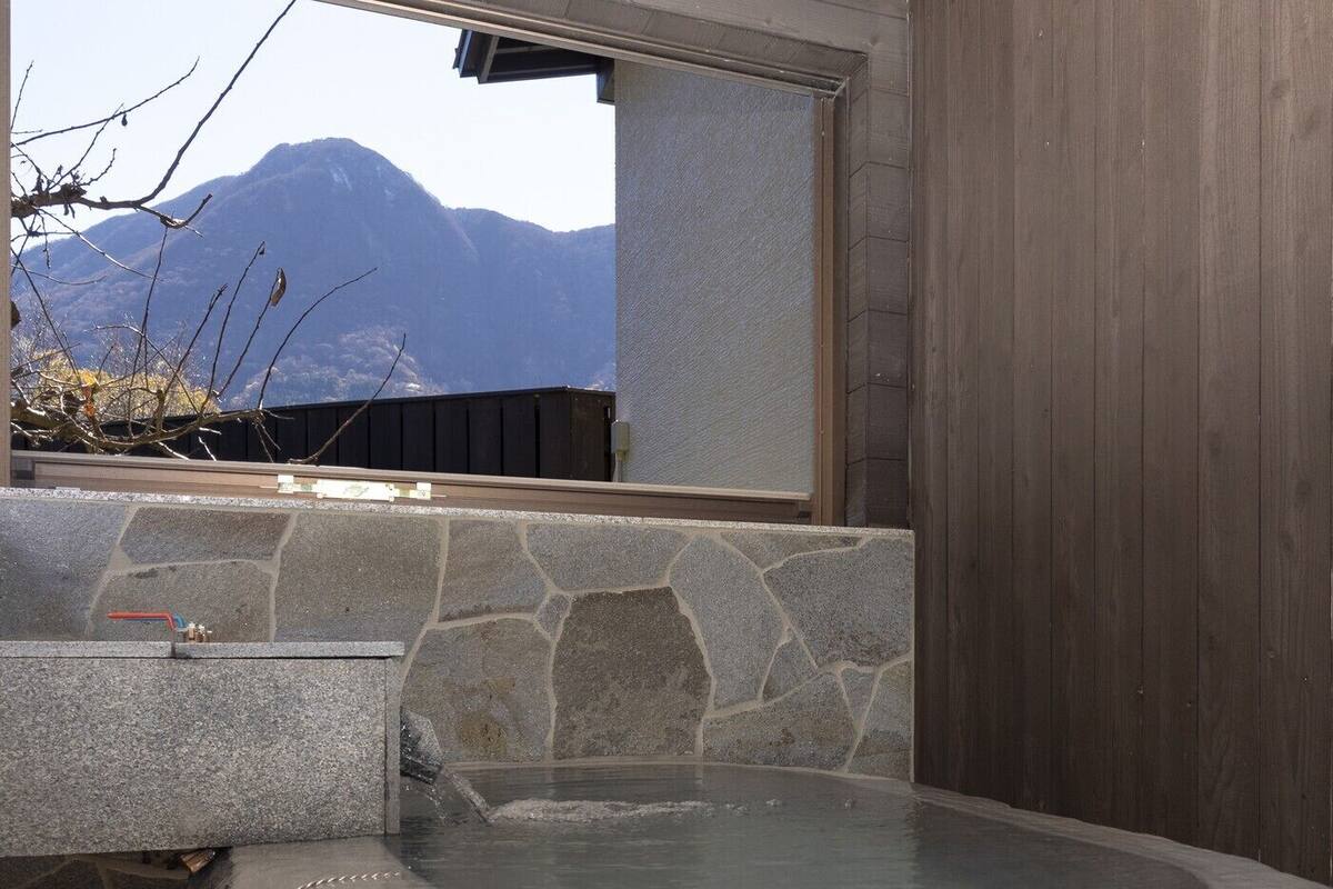 A stone-tiled hot tub area with a view of mountains through a window.