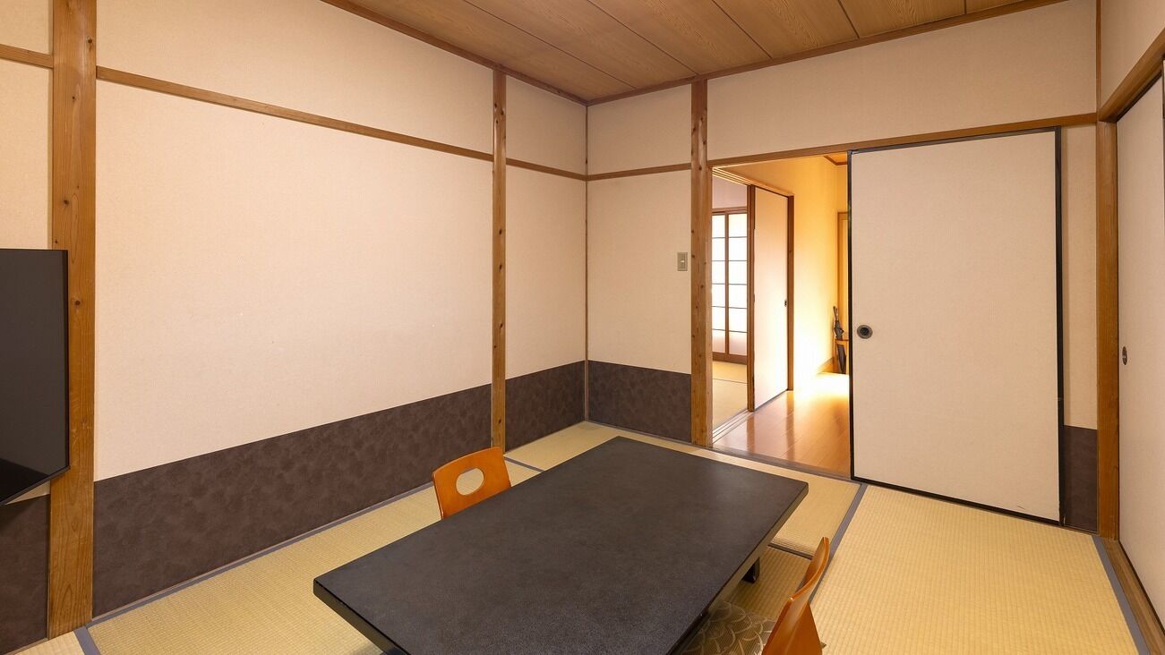 A traditional Japanese room with tatami flooring, a low table, and sliding doors.