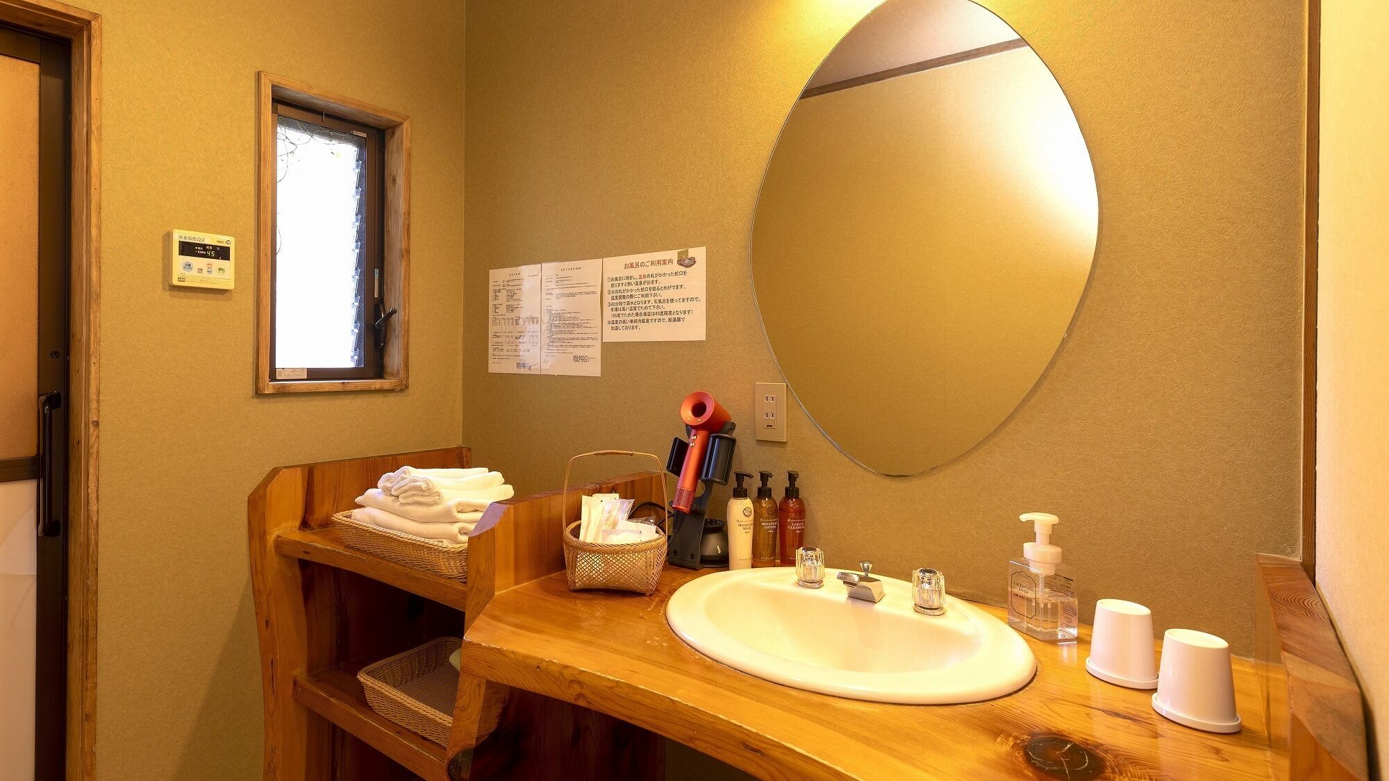 A bathroom with a wooden vanity, a large mirror, a sink, and various toiletries.