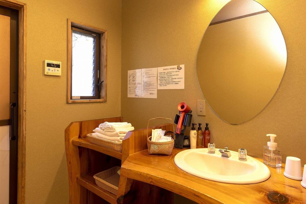 A bathroom with a wooden vanity, a large mirror, a sink, and various toiletries.
