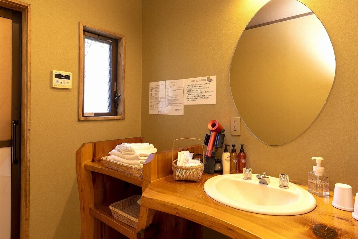 A bathroom with a wooden vanity, a large mirror, a sink, and various toiletries.