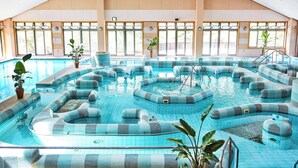 An indoor swimming pool with multiple lanes and seating areas, large windows, and a high ceiling. - Hosenbo Lodge (Seiyo)