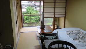 A traditional Japanese room with tatami flooring, a low table, a bed with a floral bedspread, and a sliding shoji screen. - Miharaya Ryokan (Gujo)