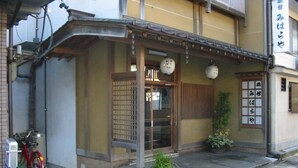 A traditional Japanese building with a wooden entrance, a bicycle parked outside, and a sign with Japanese characters. - Miharaya Ryokan (Gujo)