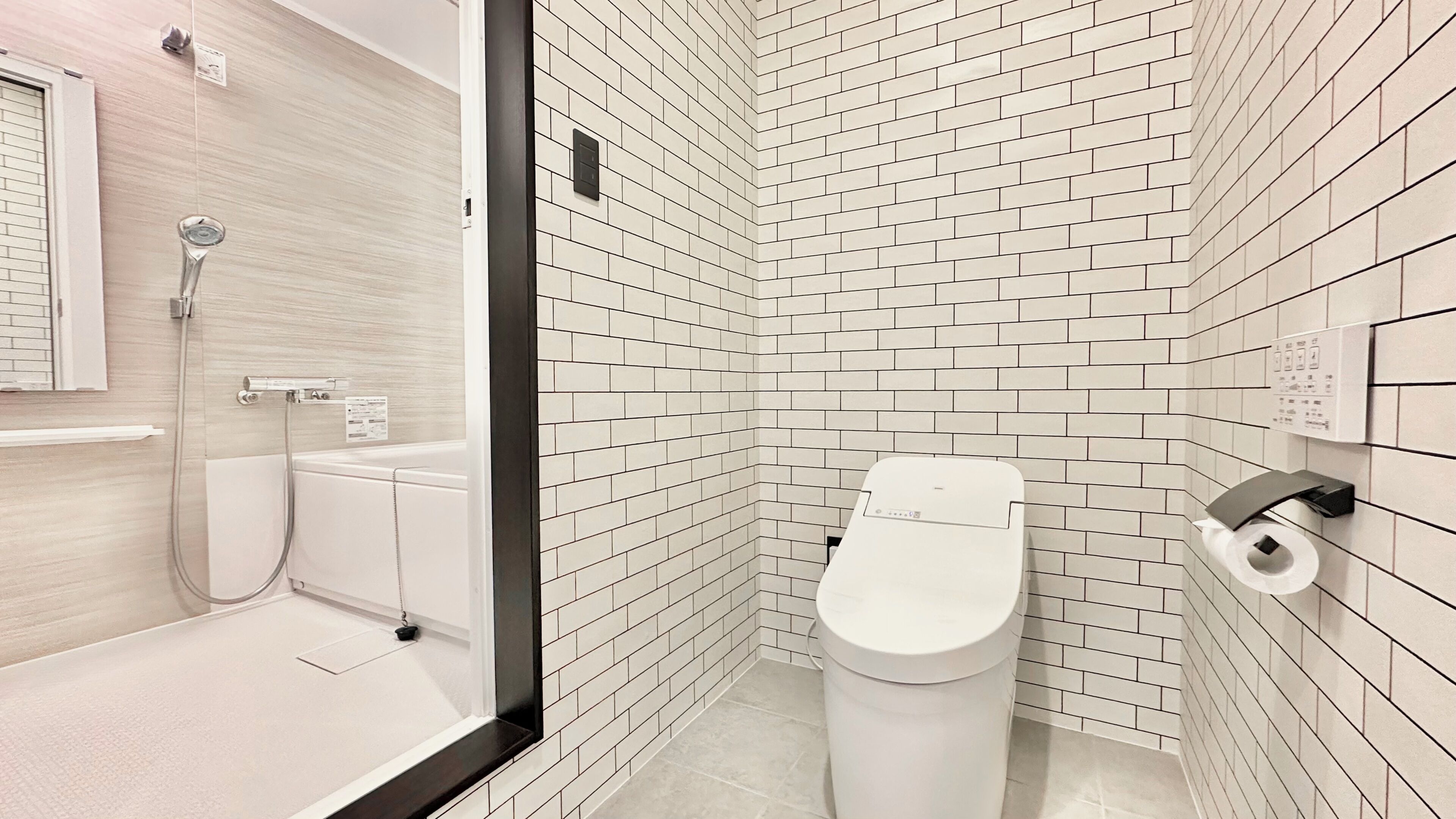 A modern bathroom with white subway tiles, a toilet, a shower, and a hand dryer.