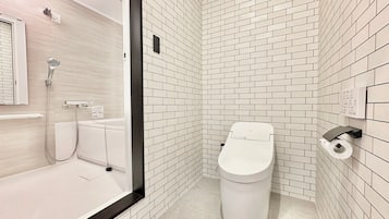 A modern bathroom with white subway tiles, a toilet, a shower, and a hand dryer.