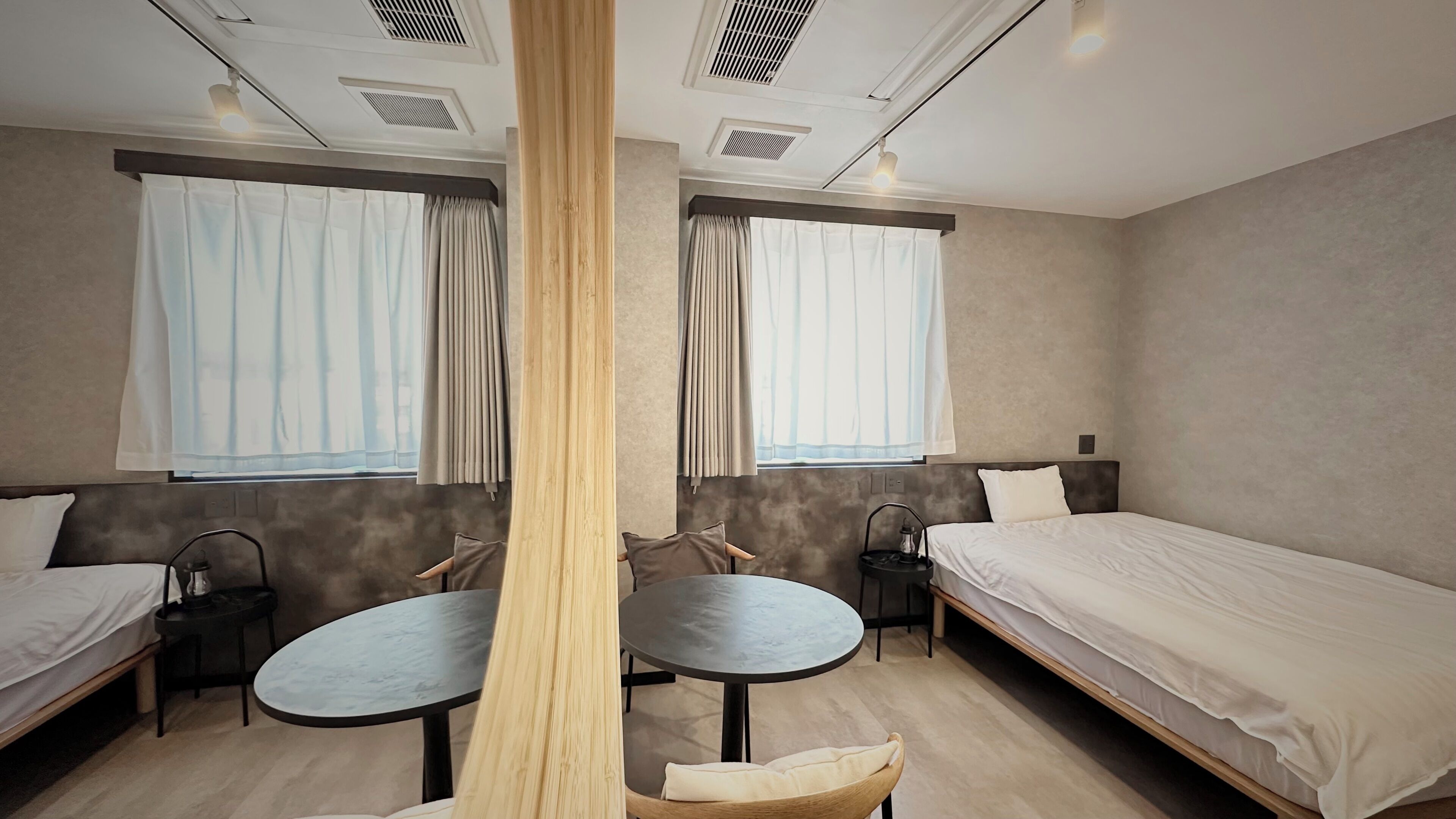 A hotel room with two single beds, a round table, and a chair.