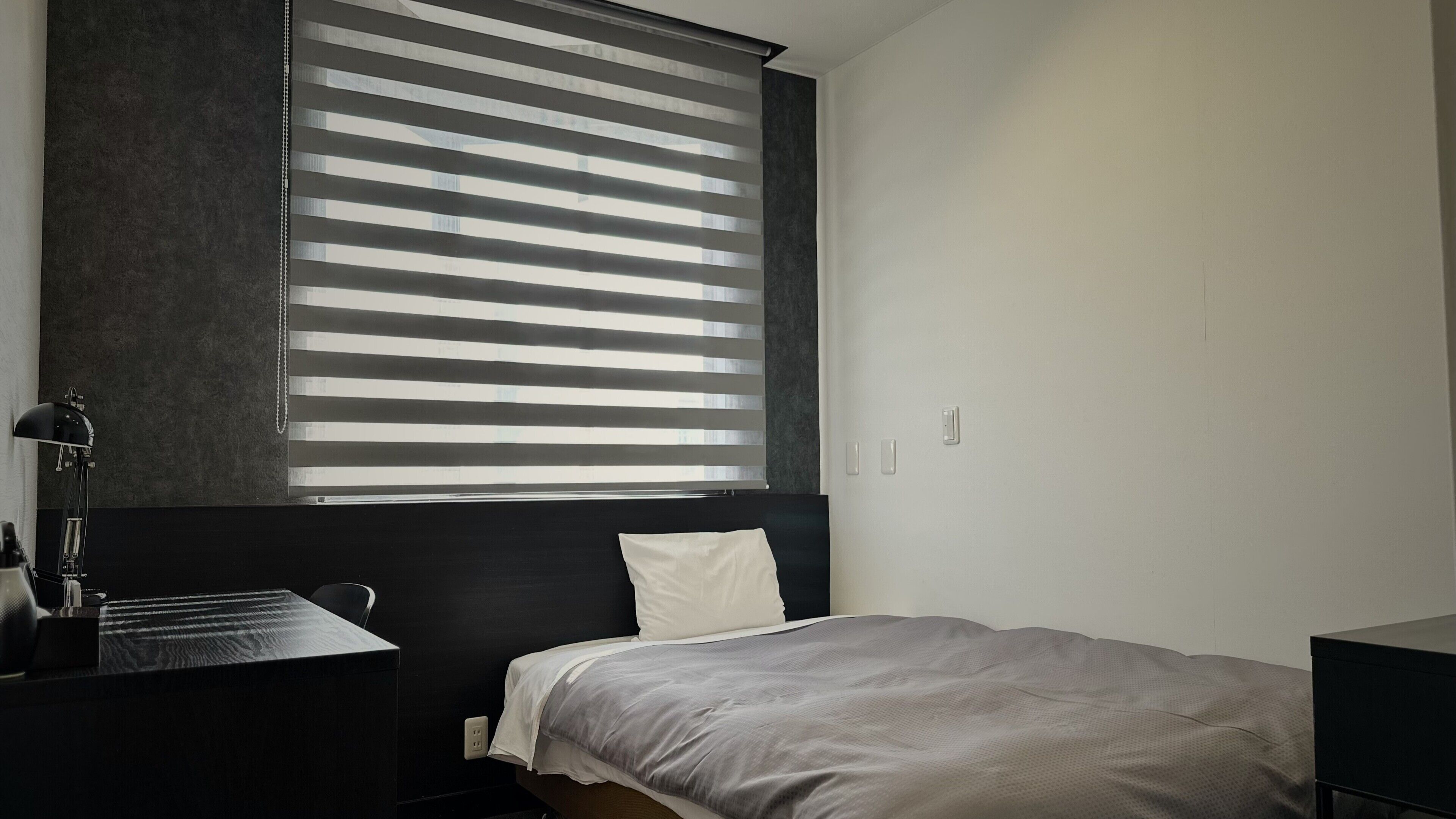 A modern bedroom with a bed, a desk, and a lamp.
