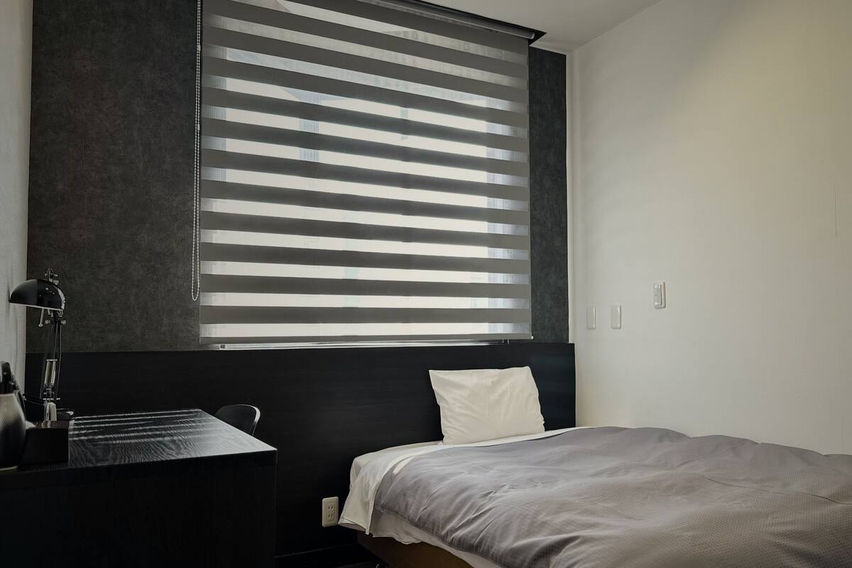 A modern bedroom with a bed, a desk, and a lamp.