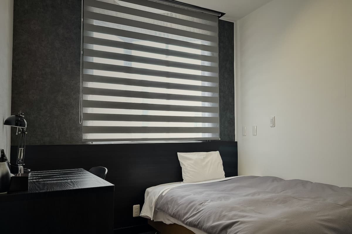 Un dormitorio moderno con cama, escritorio y lámpara.