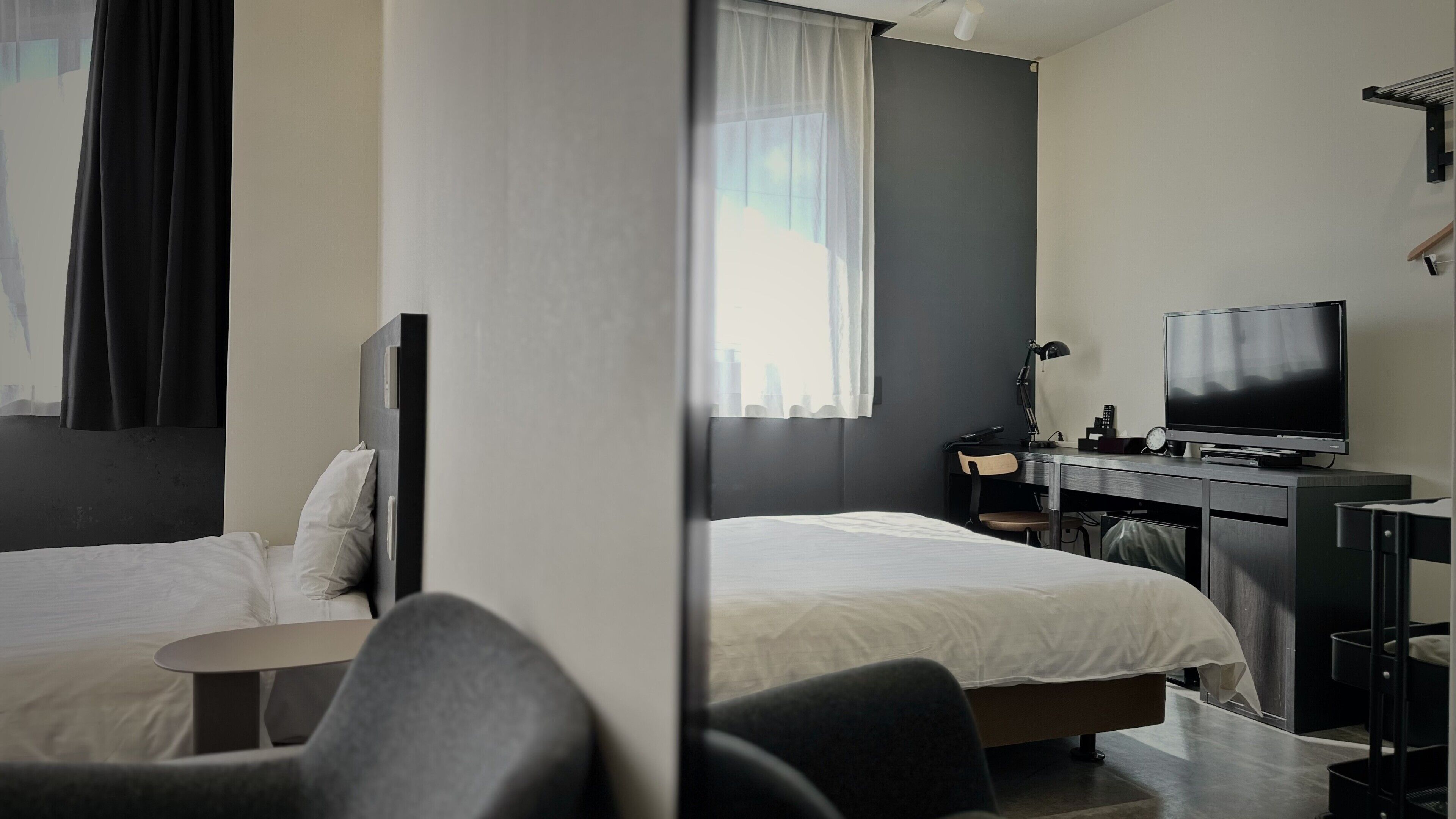 A hotel room with two beds, a desk with a TV, and a chair.