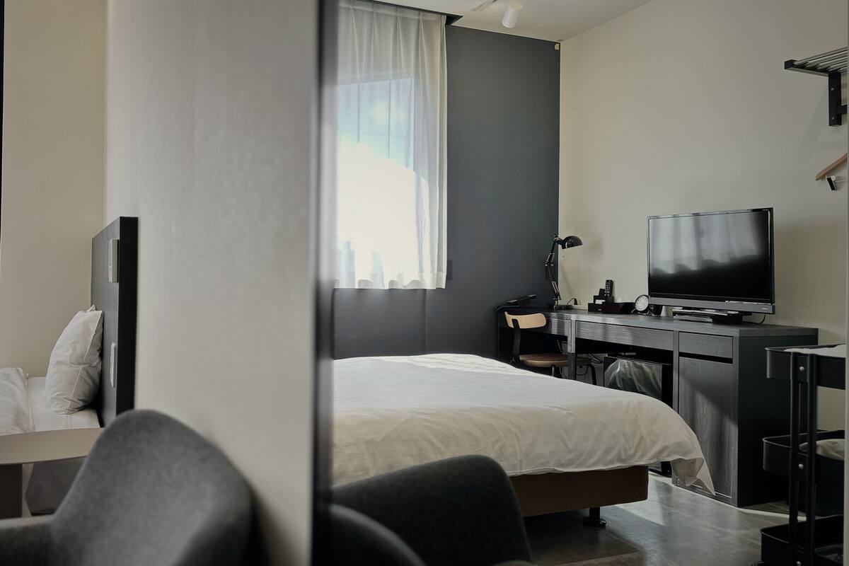 A hotel room with two beds, a desk with a TV, and a chair.
